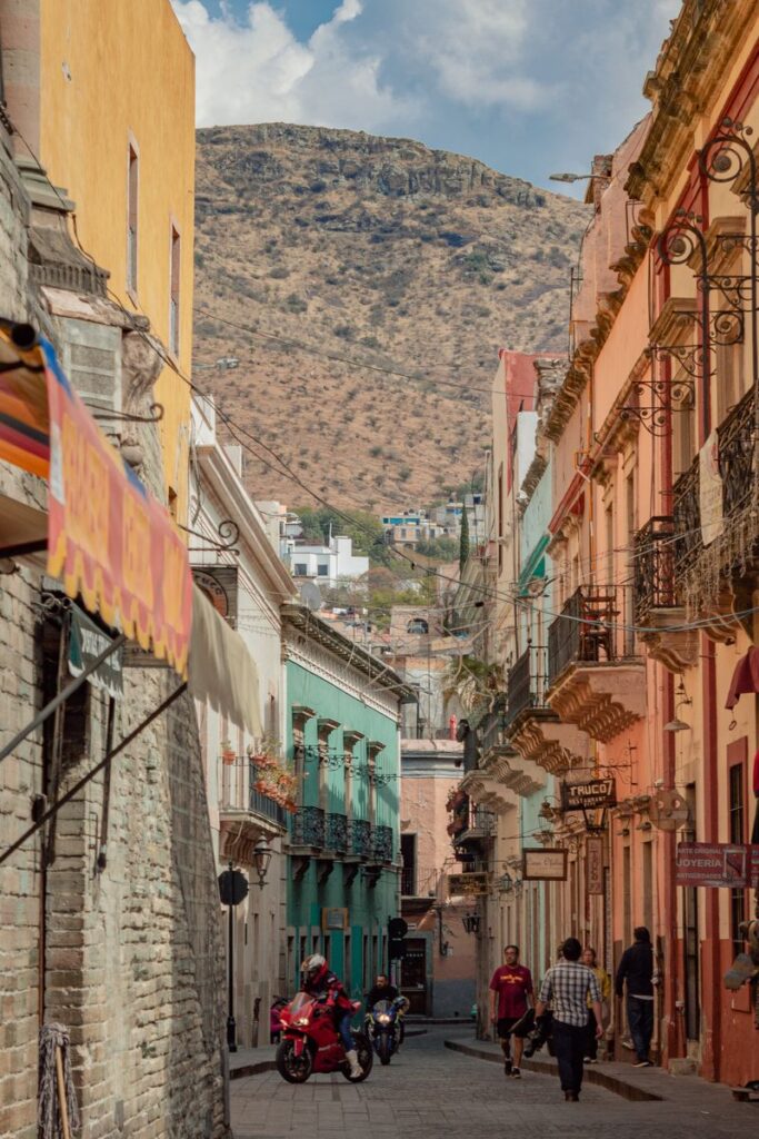 Charming Guanajuato street with colorful buildings and mountain backdrop.