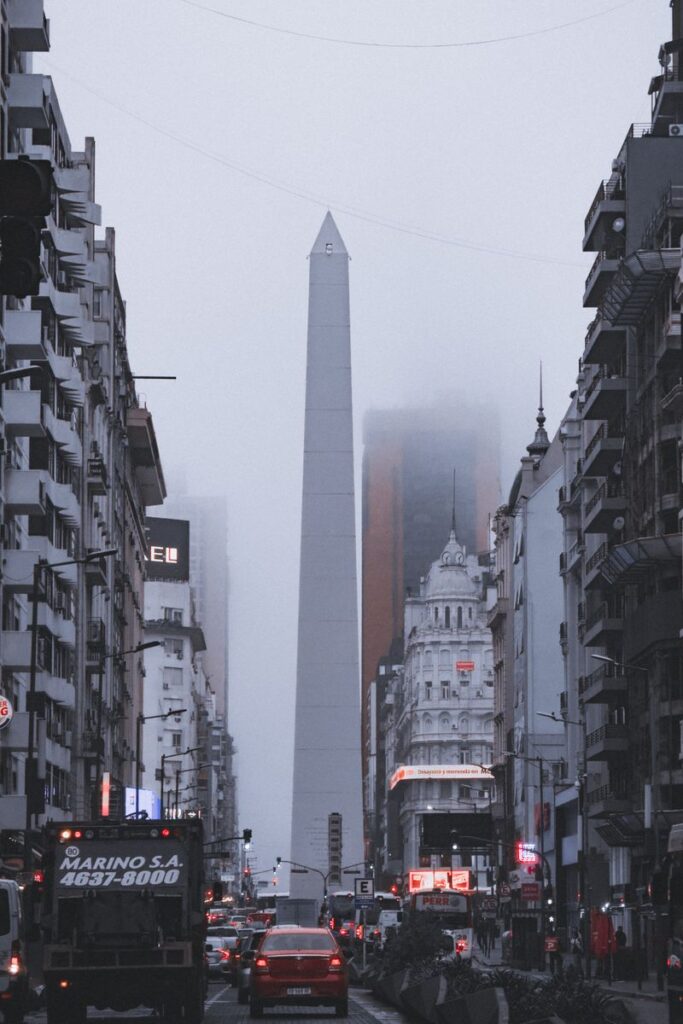 Fog envelops the iconic Obelisk in Buenos Aires, showcasing urban life and historic architecture.
