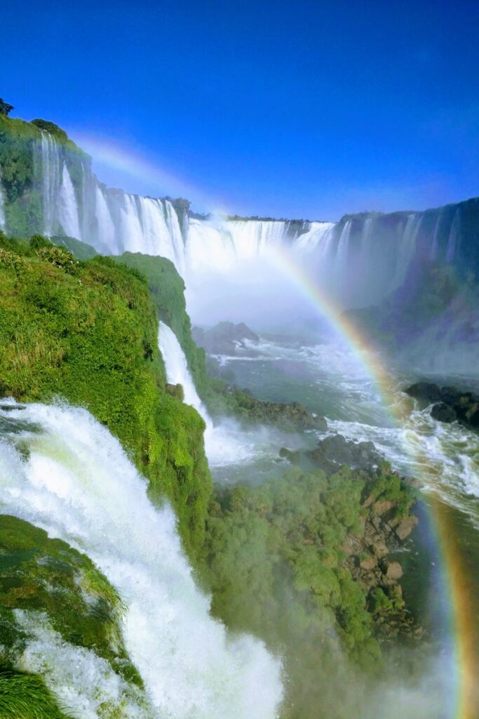 Breathtaking view of Iguazu Falls in Paraguay with vibrant rainbow and lush greenery.