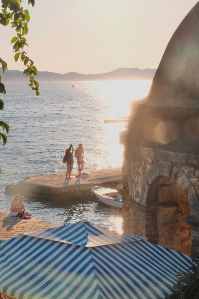 Scenic view of Zadar's waterfront during sunset with people enjoying the serene sea.