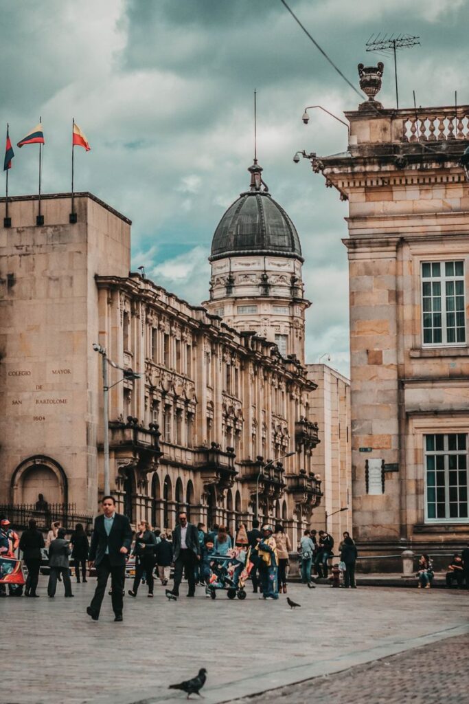 A lively scene at Bolivar Square in Bogotá, Colombia, featuring historic architecture and people walking.