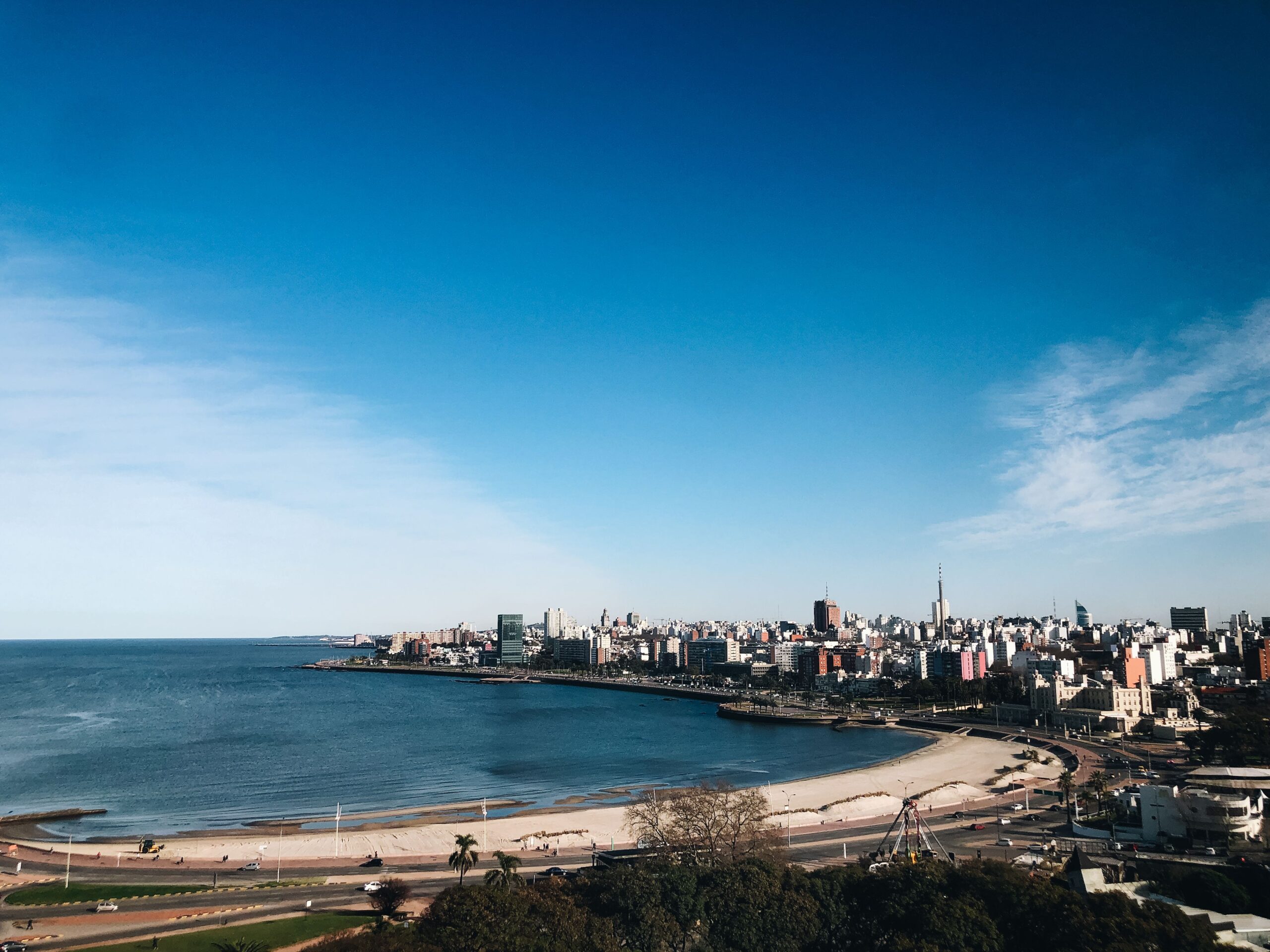 A stunning aerial view of Montevideo's coastline and urban skyline under a bright blue sky.